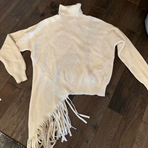 BCBG cream asymmetrical sweater with fringe detail. Size Medium. NWT